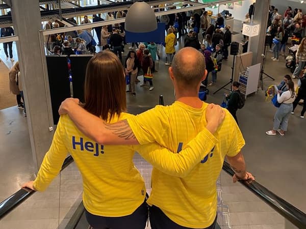 To IKEA medarbejdere på en rulletrappe skuer ned mod et IKEA varehus fyldt med deltager til en jobmatch