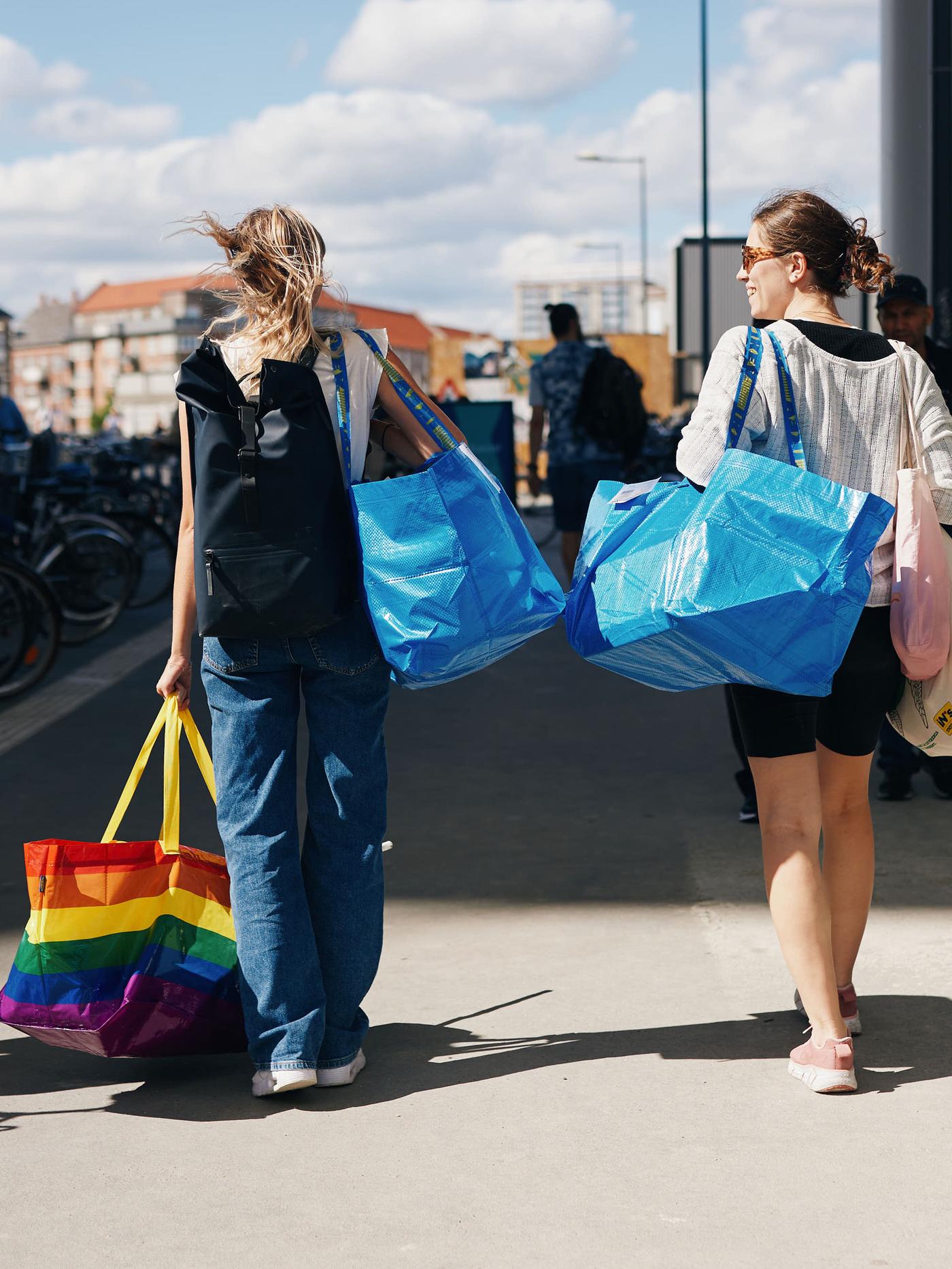 To kvinder går med IKEA poser over skuldrene.