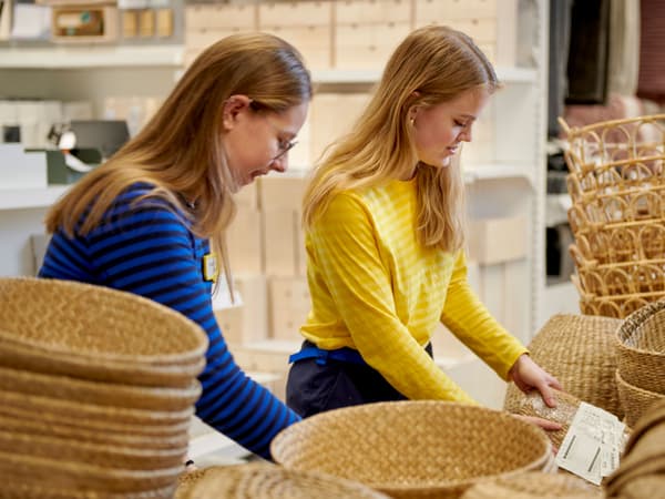 To kvinnelige IKEA ansatte rydder i oppbevaringskurver.