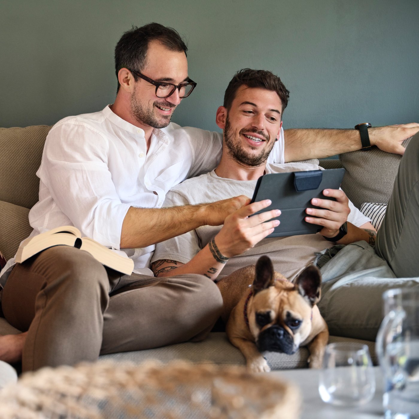 To mænd sidder i en sofa og kigger på en tablet.