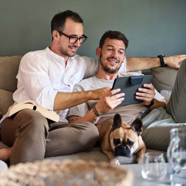 To mænd sidder i en sofa og kigger på en tablet.