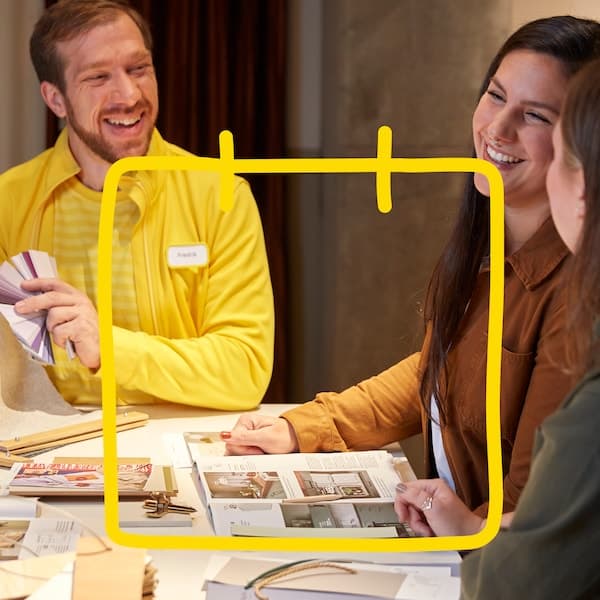 To personer sitter i et møte med en interiørdesigner som viser frem farger.