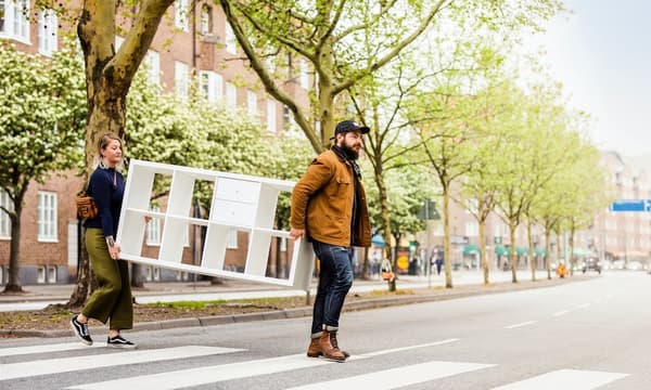 To personer som holder en KALLAX hvit hylle.