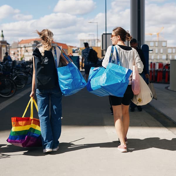 To piger går med ryggen til og med IKEA bæreposer over skuldrene.