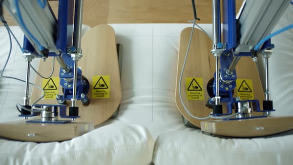 To roboter på IKEAs testlaboratorium simulerer to mennesker som sitter, under en test av holdbarheten til en sofa.