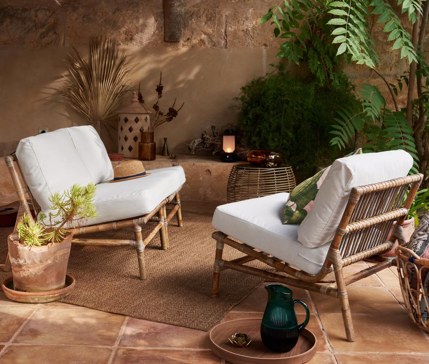 To TVARÖ siddesektioner stå overfor hinanden og skaber to lænestole i et udendørsområde med grønne planter, urtepotter og en udendørslampe.