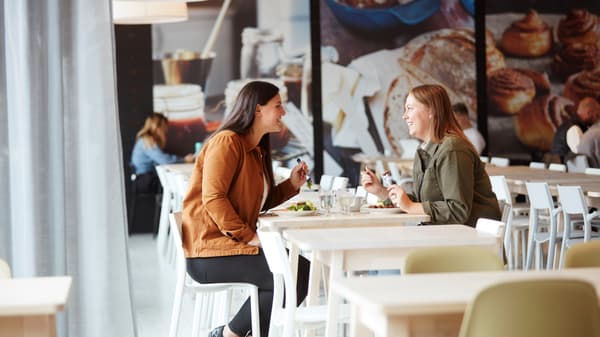To veninder sidder og spiser et måltid sammen i en IKEA restaurant.