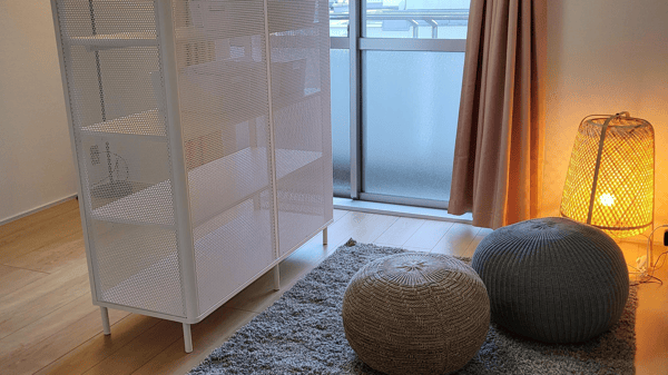 間接照明とクッションが置かれたスペースの前に白いキャビネットが置かれている。