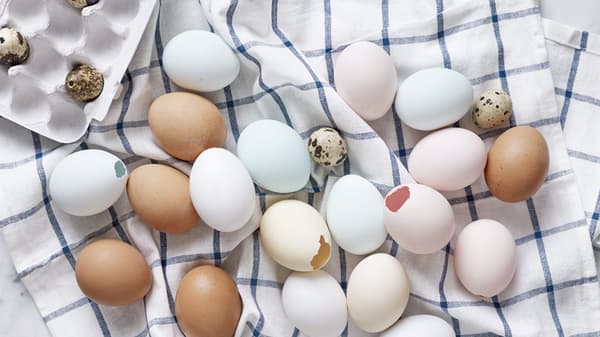 Tomma färgade ägg ligger på en vit och blå rutig handduk. 