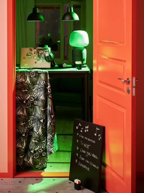 ห้องที่เปิดไฟสำหรับงานเลี้ยงพร้อมอุปกรณ์สำหรับคนเปิดเพลงอยู่บนโต๊ะ TOMMARYD/ทอมมารึด ตรงทางเข้าห้อง กระดานจดโน้ตบนพื้นมีรายชื่อเพลงที่แขกขอไว้