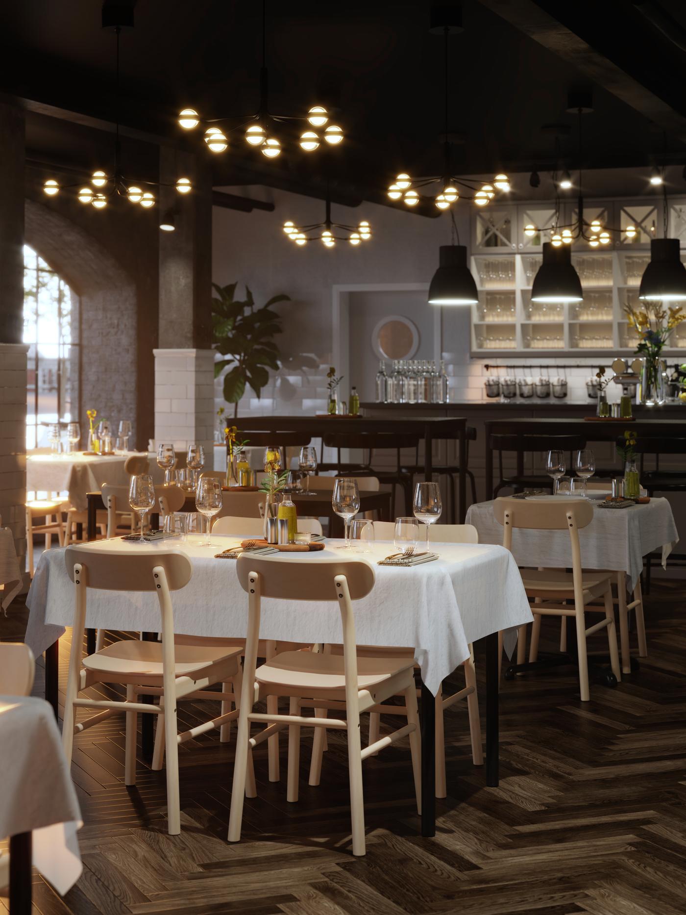 TOMMARYD-tafels gedekt om te dineren met witte tafelkleden, STORSINT-wijnglazen en bloemen in een ruim restaurant met parketvloer.