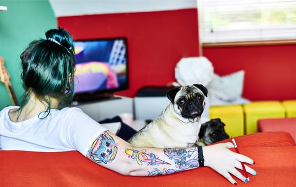 Toni et son chien assis sur un canapé rouge.