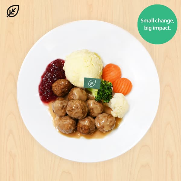 Top-down plate of meatballs, mashed potatoes, carrots, broccoli, cauliflower and lingonberry sauce on wood, with “Small change, big impact” badge.