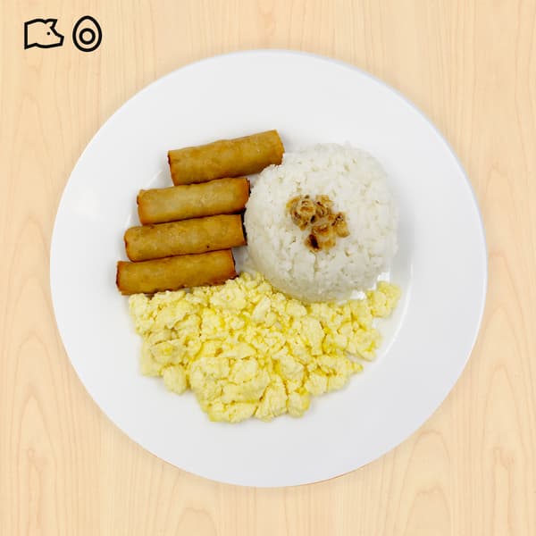 Top-down view of a white plate with rice, scrambled eggs, and three golden fried rolls on a light wood table; warm, appetizing meal.