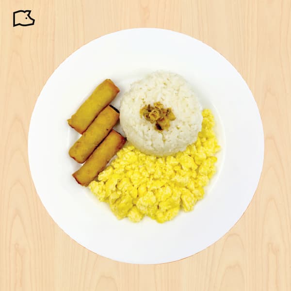 Top-down view of a white plate with rice, scrambled eggs, and three golden fried rolls on a light wood table; warm, appetizing meal.