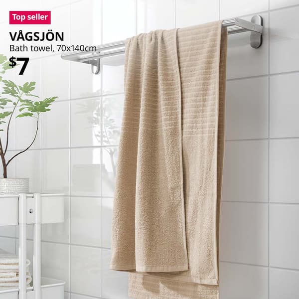 Top seller tag. Beige VÅGSJÖN bath towel hanging over a metal rail in the bathroom. Price: $7.