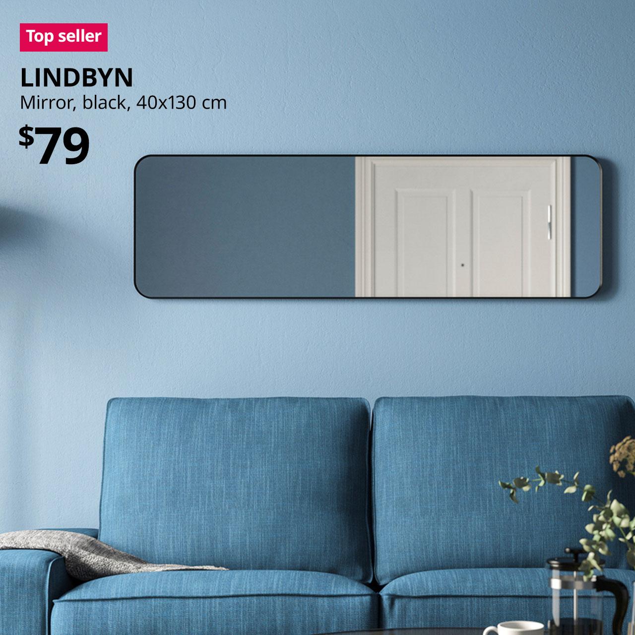 Top seller tag. Black LINDBYN mirror hanging on a blue wall in a living room. Price: $79.