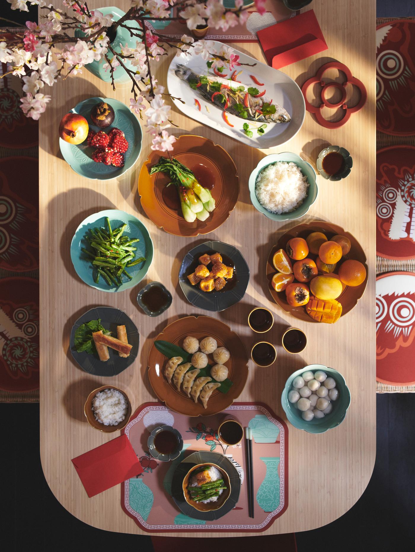Top view of a dining table set with FÖSSTA placemats and plates, adorned with a selection of typical Chinese New Year food.