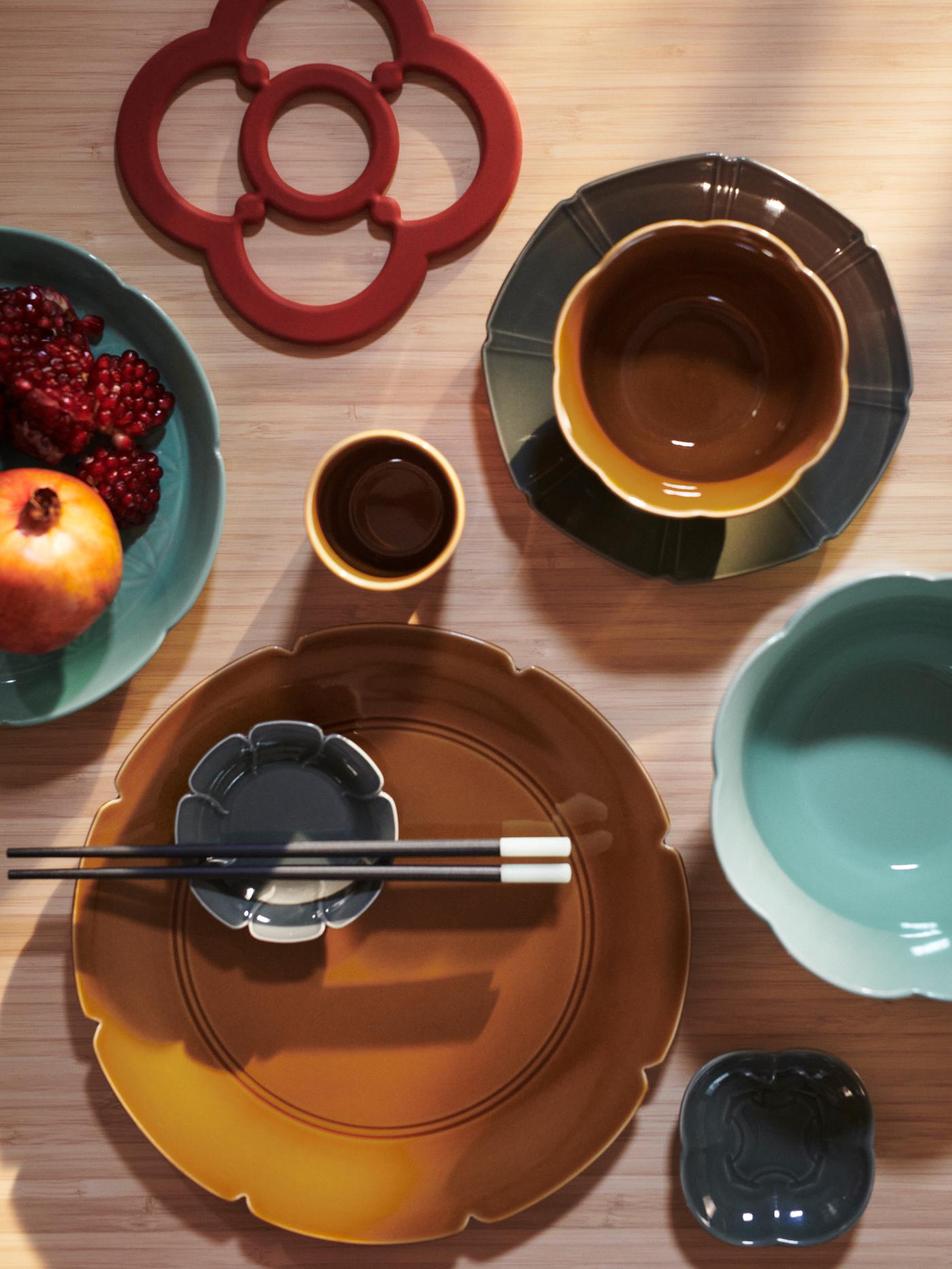 Top view of a set dining table with a FÖSSTA pot stand next to a selection of FÖSSTA plates and bowls.