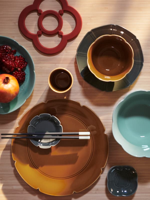Top view of a set dining table with a FÖSSTA pot stand next to a selection of FÖSSTA plates and bowls.