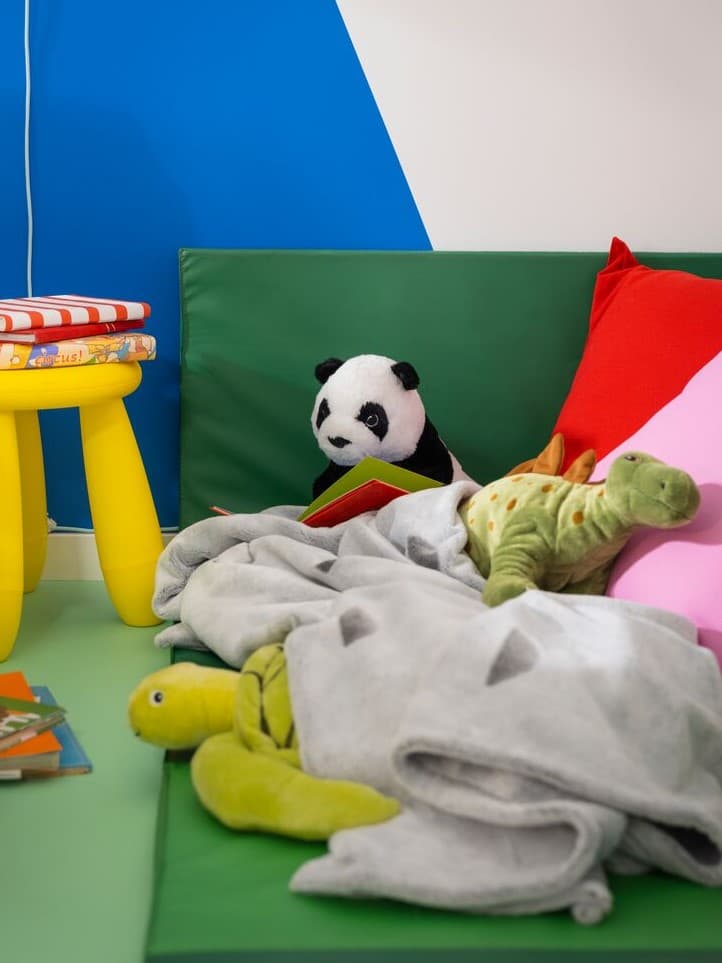 Toys and play
Colorful soft toys and play items scattered on a green play mat near a small yellow table.