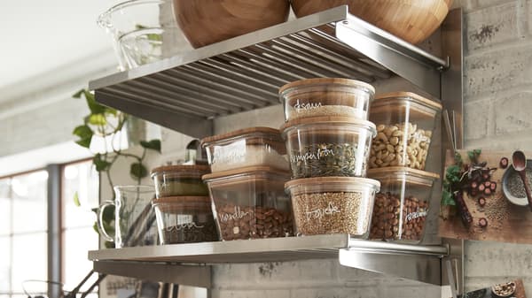 Transparent containers with grains and beans on the lower shelf of a KUNGSFORS suspension rail with shelf/wall grid.