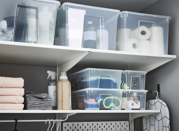 Transparent SAMLA plastic boxes stacked on shelves and filled with laundry-related items.