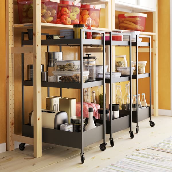 Tre carrelli neri sotto uno scaffale in pino – IKEA