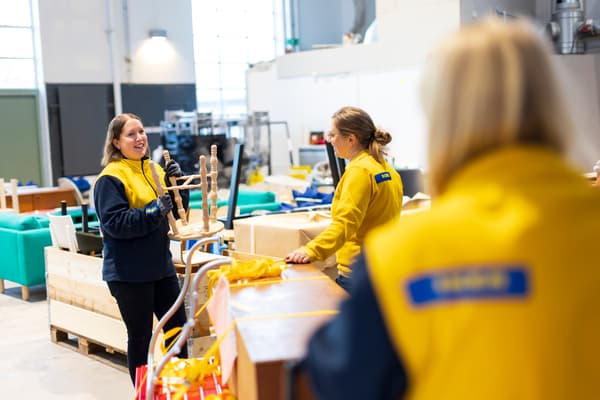 Tre IKEA-medarbetare står vid en grupp möbler och pratar med varandra