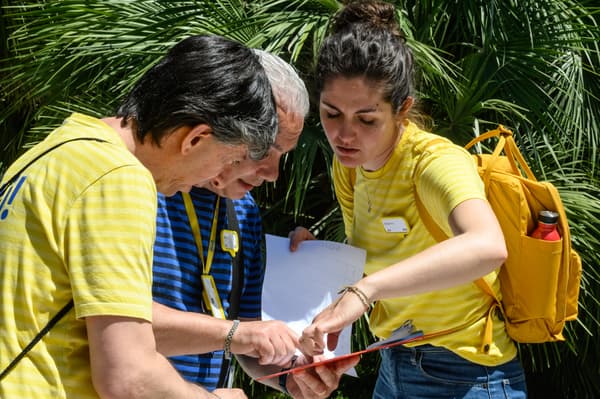 Tre persone consultano un documento su una cartelletta. 