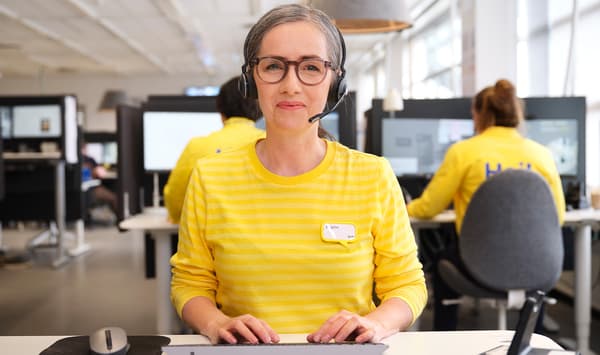 Treballadora d’IKEA somrient mentre atén amb auriculars des de l’oficina.
