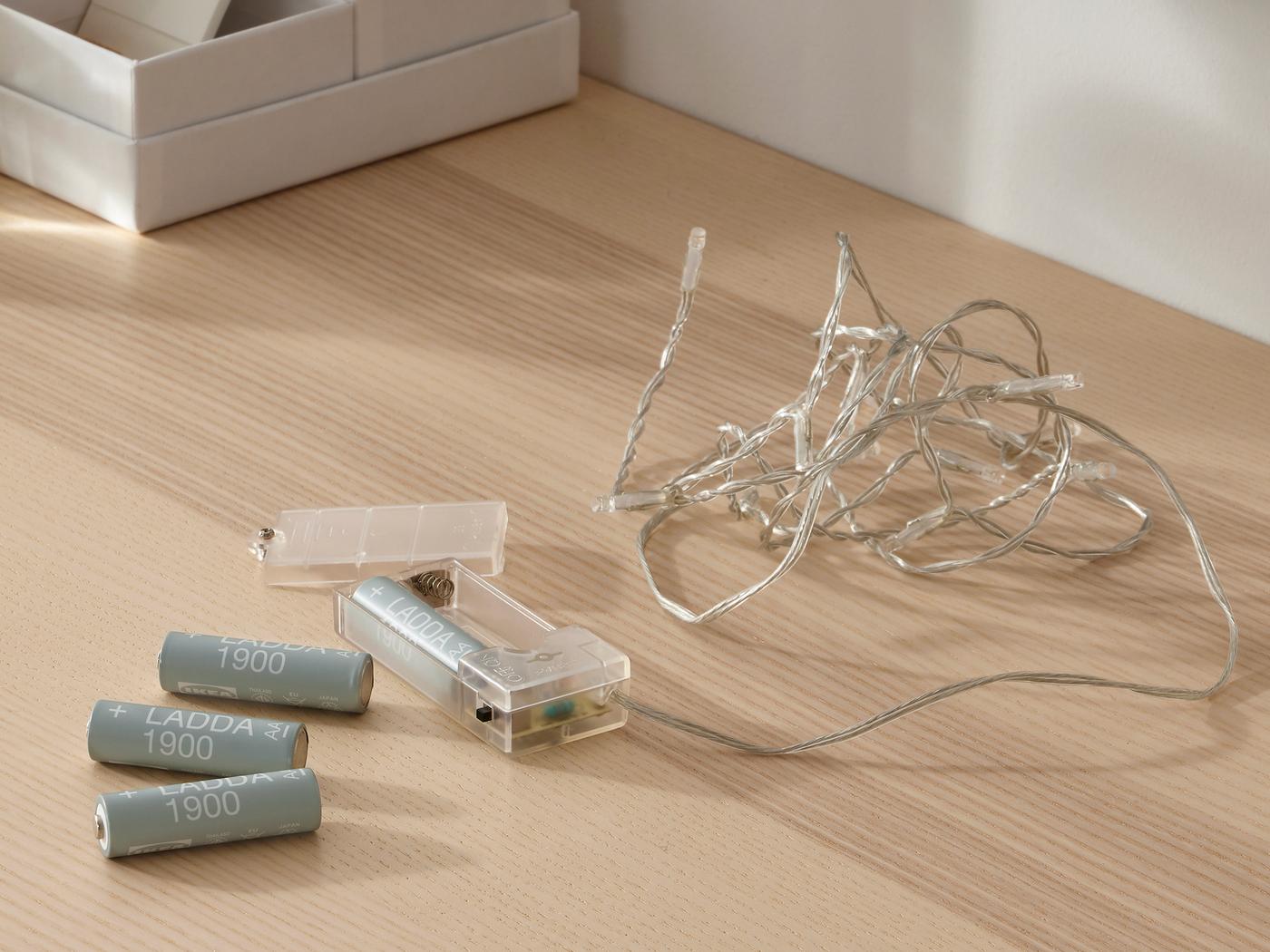 Tres baterías recargables LADDA sobre una mesa junto a una unidad de recarga que contiene una sola batería recargable LADDA.