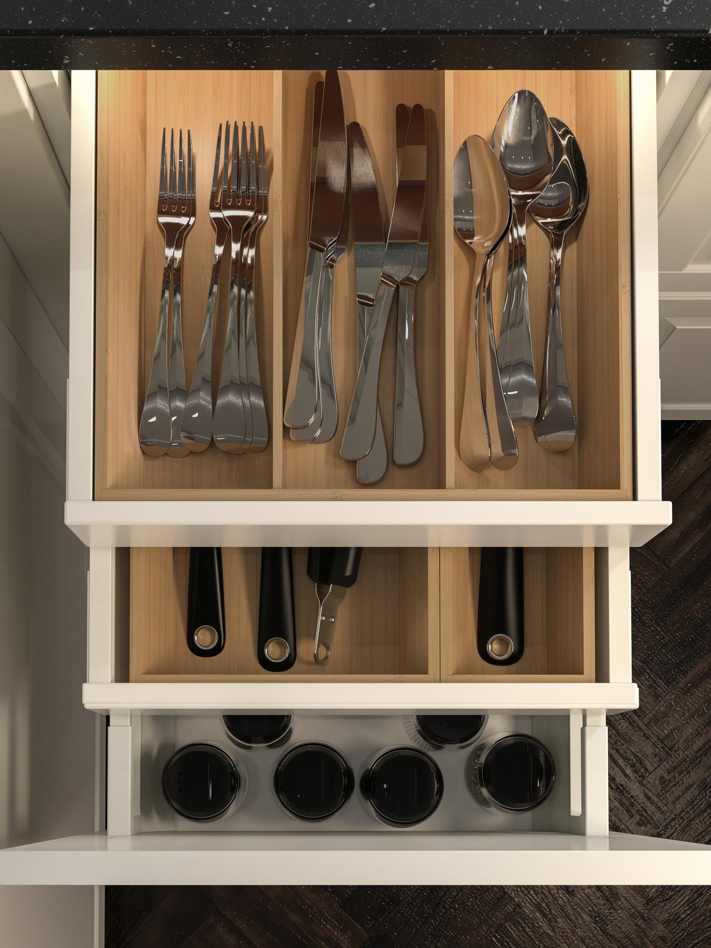 Tres cajones de cocina abiertos iluminados con luz LED incorporada. Los cajones contienen cubiertos, utensilios y tazas.