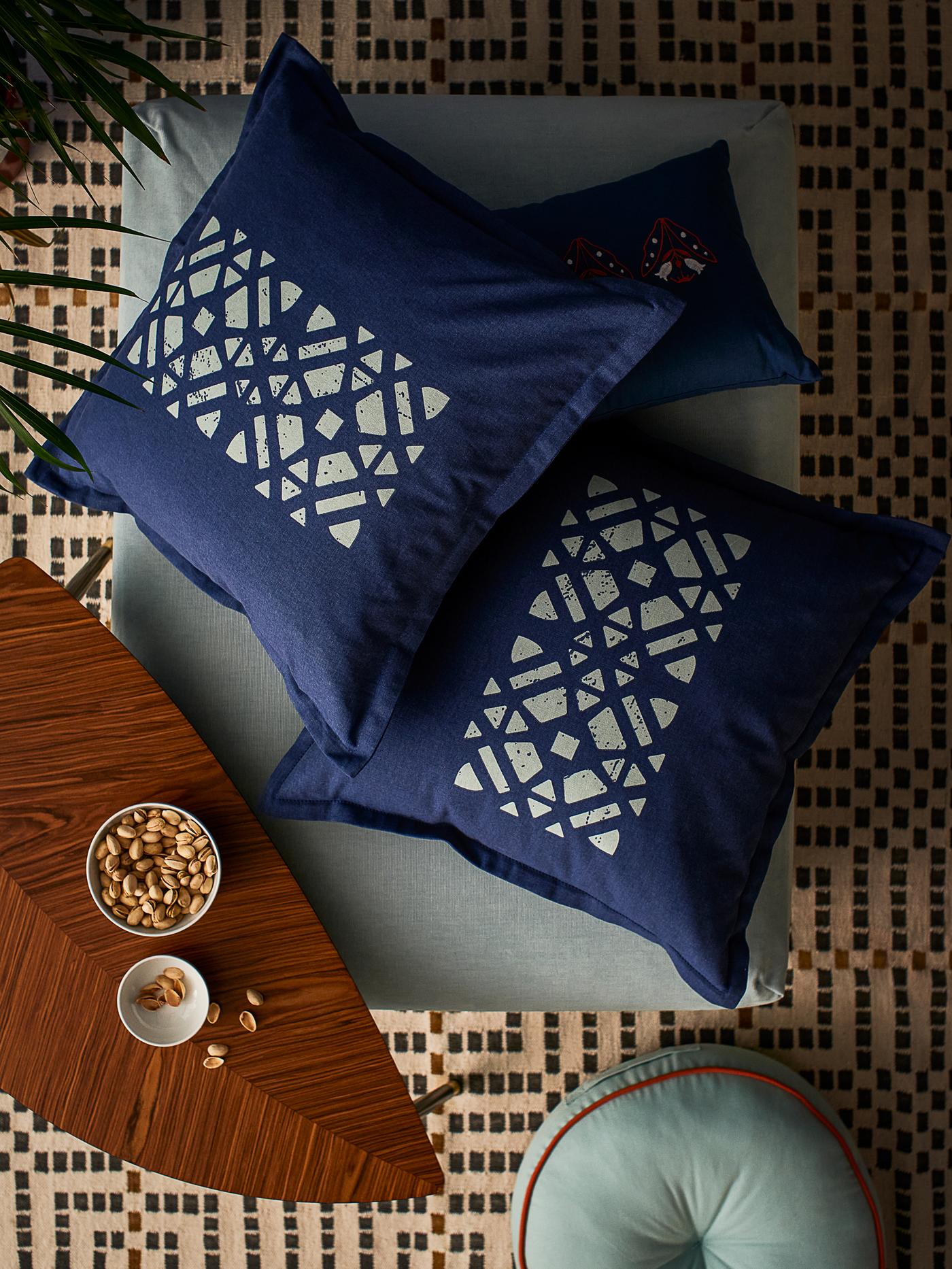 Tres cojines con fundas GOKVÄLLÅ sobre una otomana. Junto a ella, hay un cojín para suelo GOKVÄLLÅ.