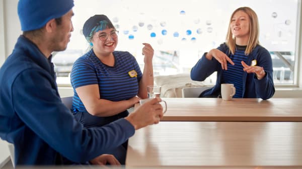 Tres colaboradores con el uniforme IKEA conversando y riendo.