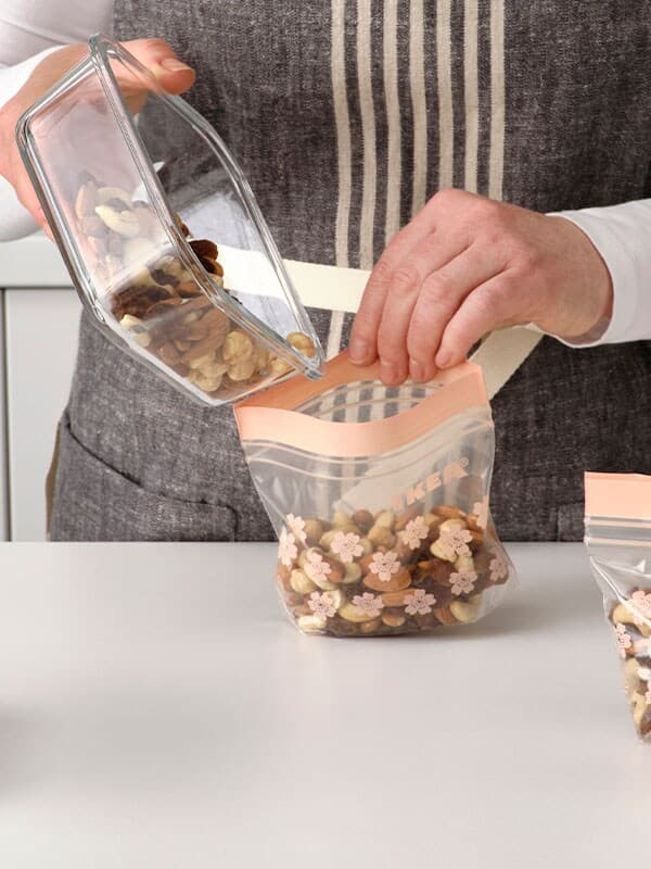 Tres contenedores SORTERA blancos en una habitación con azulejos blancos donde uno está lleno de papel marrón.