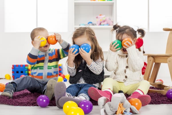 Tres niños pequeños en una habitación de juegos. Juegan poniendo pelotas plásticas en sus ojos.