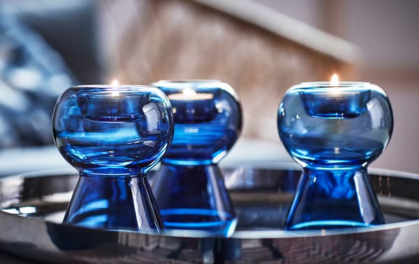 Tres portavelas de vidrio azul sobre una bandeja de plata.