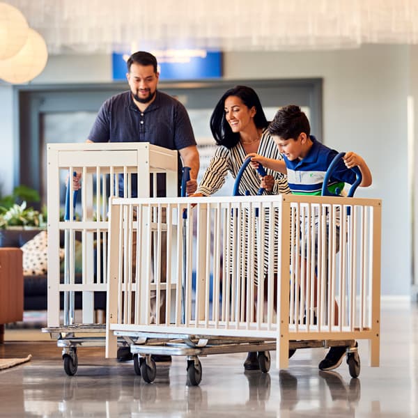 Tříčlenná rodina veze do obchodního domu IKEA použité dětské postýlky.