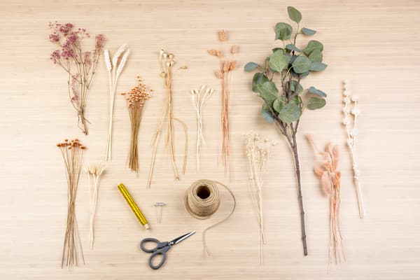 Trockenblumen, eine Kordel und eine Schere liegen auf einem Tisch.
