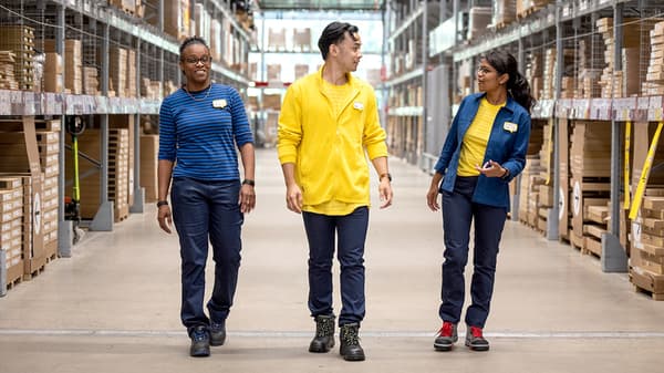 Trois collaborateurs IKEA marchent dans un entrepôt.