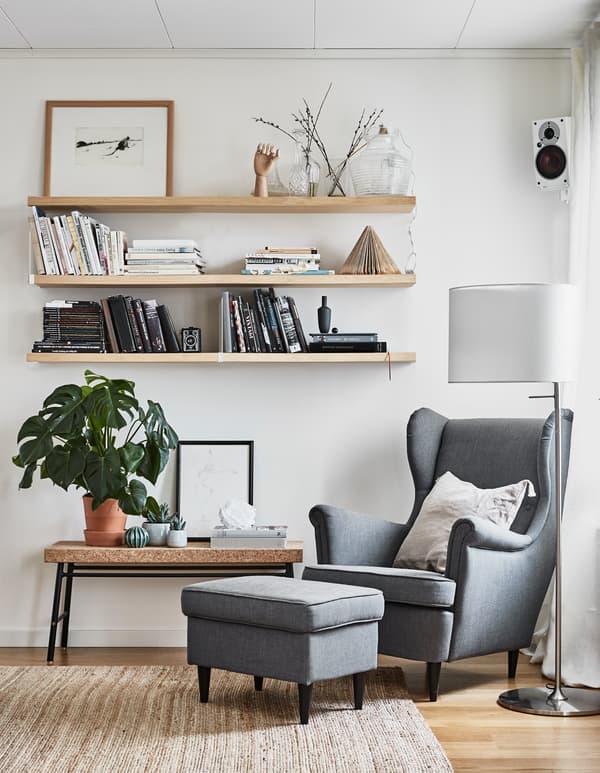 Trois étagères murales et une banquette placés à côté d’un fauteuil et d’un repose-pieds