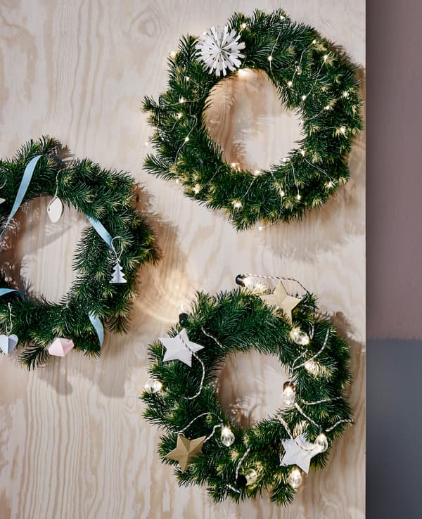 Trois guirlandes de Noël toutes simples accrochées à une planche en bois.