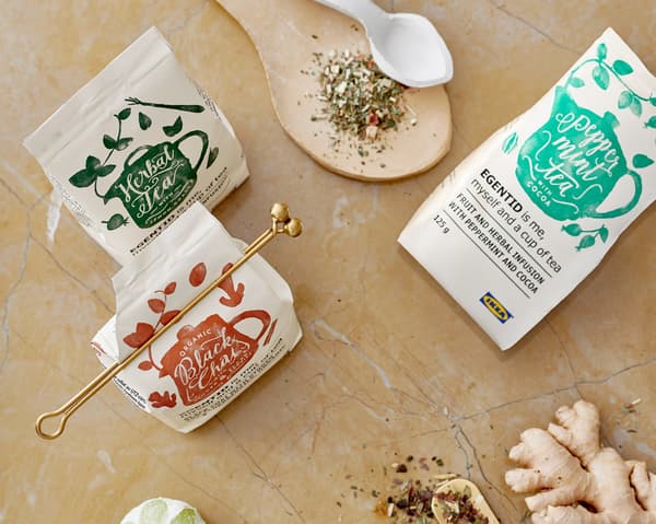 Trois paquets de thés IKEA EGENTID entourés d'herbes et d'épices utilisés pour les aromatiser.
