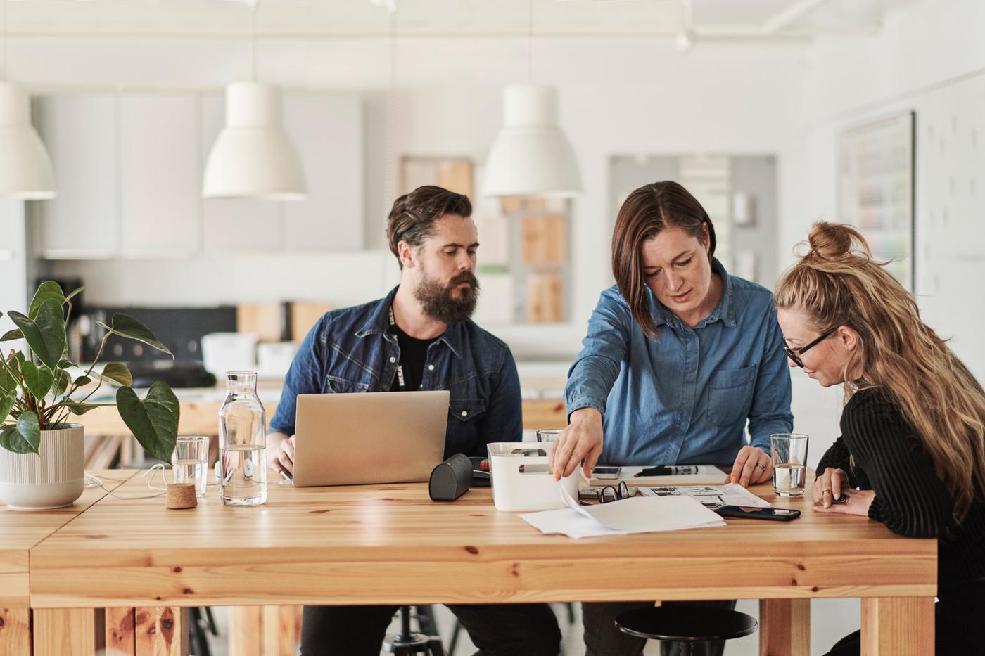 Trois personnes discutent autour d'une table.