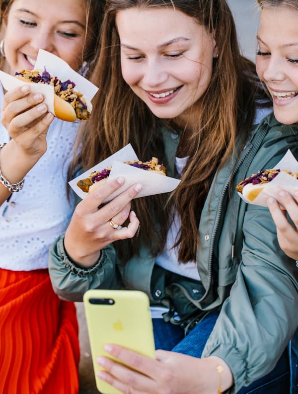 Trois personnes en train de prendre un selfie avec des hot-dogs végétariens.