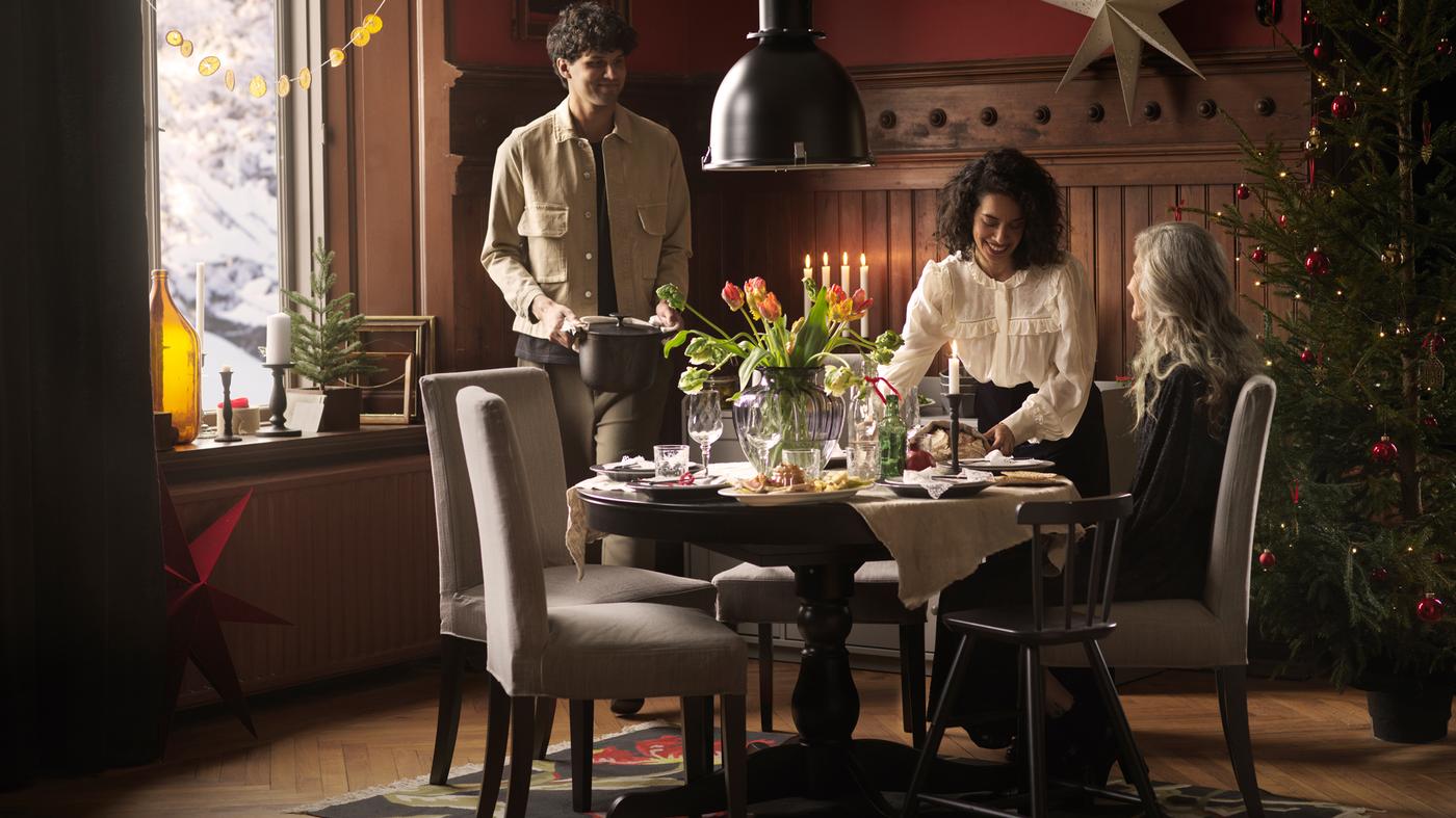 Trois personnes réunies pour un repas de fête autour d’une table ronde INGATORP