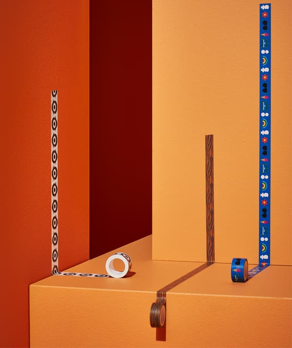 Trois rouleaux de ruban washi à motifs collés sur des murs et des marches oranges et rouges.