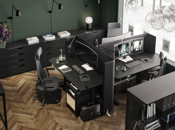 Trois tables TOMMARYD, chacune complétée par une chaise de bureau JÄRVFJÄLLET et un écran de séparation, à côté d’une fenêtre. Un caisson à tiroirs GALANT est installé à proximité.