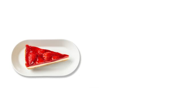 Trojúhelníček jahodového cheesecaku na bílém oválném talířku